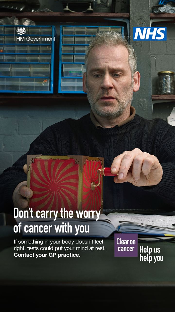 A man sits in a garage with a jack in a box. The box is stripy red.