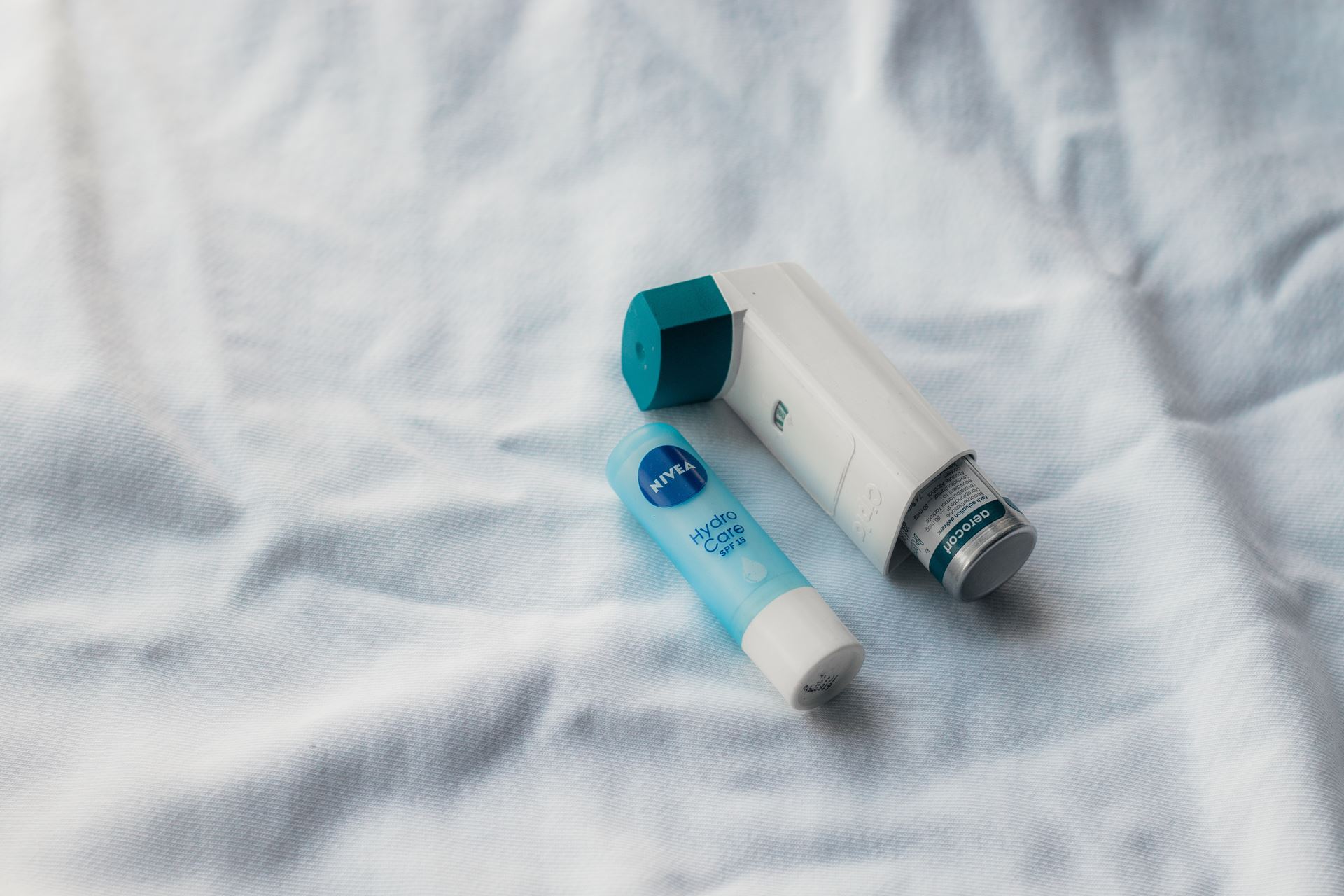 A white and blue inhaler next to a pale blue lip balm